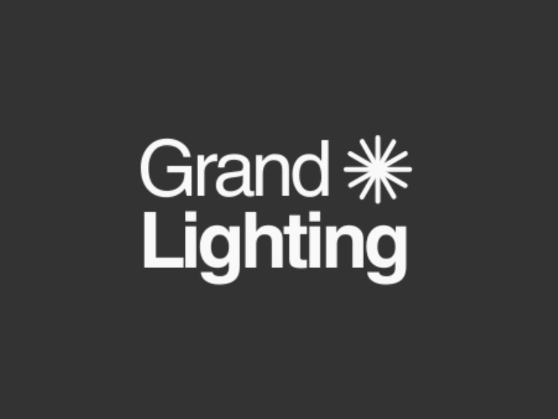 Logo of Grand Lighting featuring the company name in bold white text against a dark background, accompanied by a starburst graphic.
